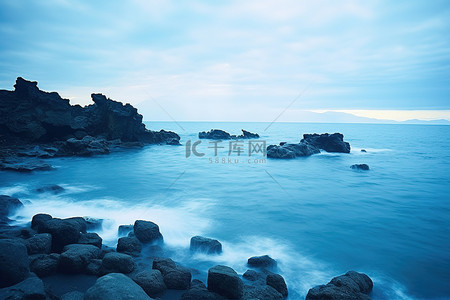 一大片蓝色的水域，后面有岩石海岸