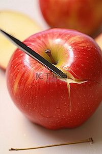 切开的蛇果背景图片_使用附有蓝色棍子的勺子将苹果切开
