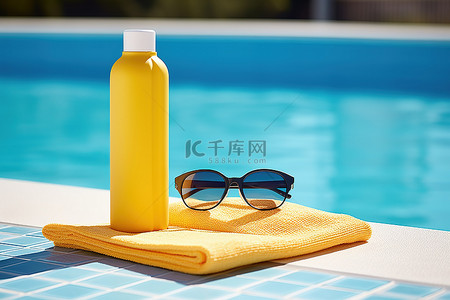 水瓶太阳镜和泳池旁的蓝色毛巾