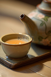一个橙子和茶杯放在绿茶壶前面