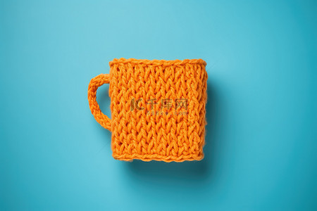 异常背景图片_蓝色背景上的橙色针织杯