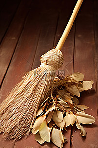 扫地小帮手背景图片_一把扫帚放在一堆干桉树叶上