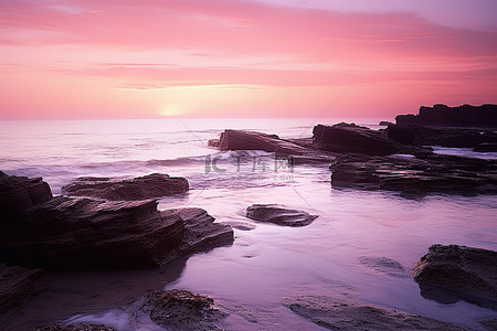 海洋有粉红色的天空，在岩石上形成紫色的天空