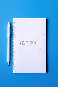 圆珠笔蓝色背景图片_蓝色背景上白色笔旁边的白色记事本