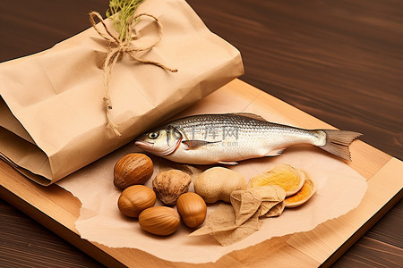 食品栗子背景图片_木盘旁边有一个纸袋，里面有一条鱼和一些坚果