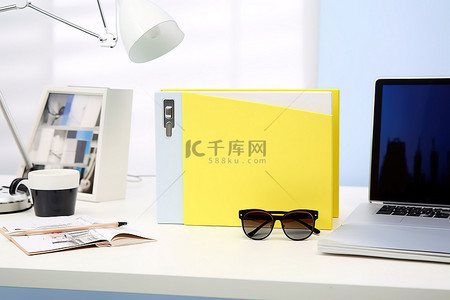 白纸活页夹装在黄色和蓝色三角形盒子里，上面有两个太阳镜和眼镜，放在白色桌子上