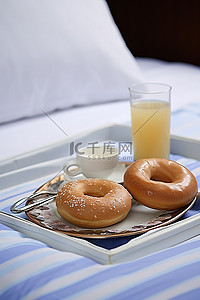 食物一杯饮料背景图片_床上托盘上放着两个甜甜圈和一杯饮料