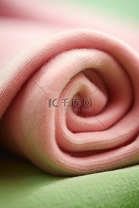 一条粉红色的毛巾放在绿色的表面上