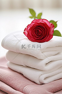 一朵粉红玫瑰坐在四块亚麻毛巾的中间