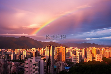 彩虹山背景图片_一座拥有高耸建筑物的城市，彩虹在它们上方闪耀