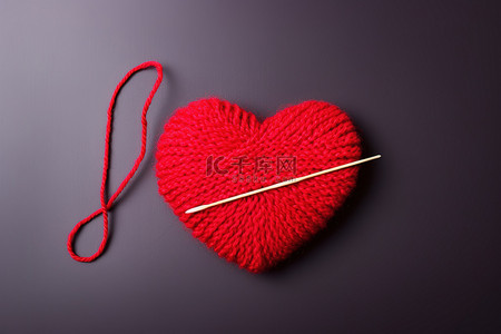 红色心形背景图片_红色羊毛和一根织针位于红色心形的顶部