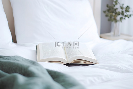 一本书放在一张带枕头的白色床上