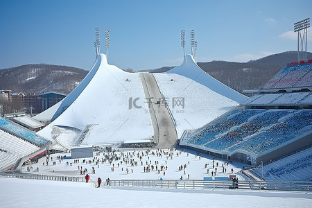 跳台滑雪滑雪背景图片_一个体育场被雪覆盖，有一排排的人和一个大跳台滑雪场