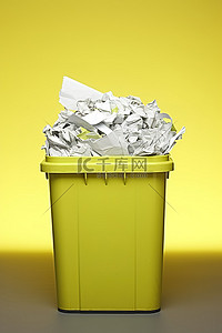 垃圾箱和背景图片_一个装满纸张和碎纸片的黄色垃圾箱