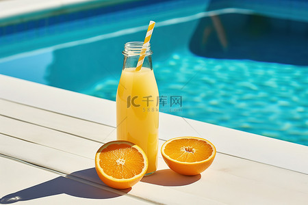 池边桌子上放着一瓶橙汁和橙子