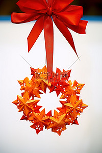 圣诞花环红色背景图片_挂在红色蝴蝶结上的彩色圣诞花环