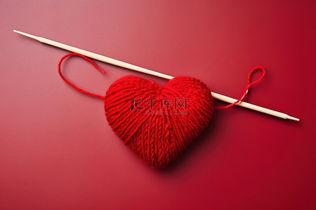 红色羊毛和一根织针位于红色心形的顶部