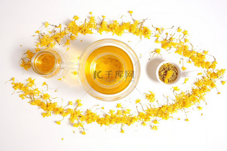 一些黄色的花旁边放着一个茶壶和一杯蜂蜜