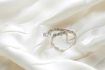 银色结婚戒指位于白色蕾丝礼服之上