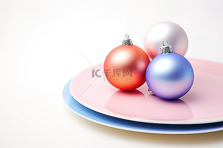 白色底座背景图片_白色底座上橙色和蓝色盘子中的两个圣诞装饰品