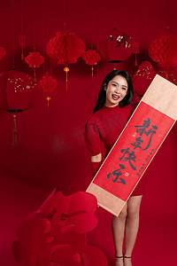 传统习俗剪纸摄影照片_新年气氛红色背景下的一位亚洲青年女性拿着春联