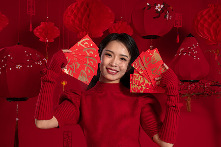 春节习俗摄影照片_新年气氛红色背景下的一位亚洲青年女性拿着红包