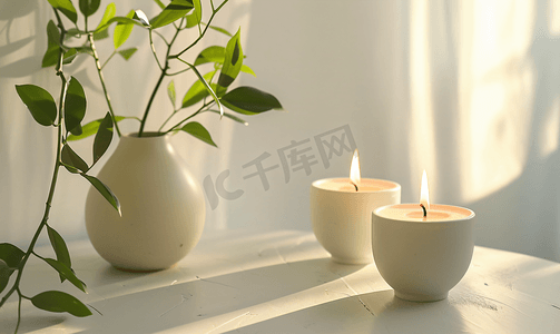 美丽燃烧的蜡烛与绿叶在花瓶在白色桌子