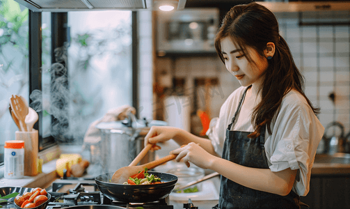 劳动节目录摄影照片_亚洲人青年女人在厨房里做饭