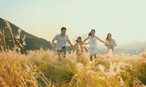 注视镜头摄影照片_亚洲人快乐家庭在草地上奔跑