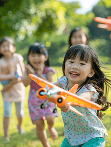 秋天人像摄影照片_亚洲人拿着玩具飞机在公园玩耍的快乐儿童