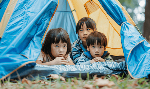 亚洲人户外露营的儿童趴在帐篷里看电影