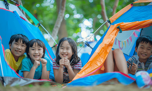 电影活动摄影照片_亚洲人户外露营的儿童趴在帐篷里看电影