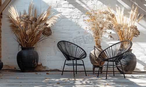 芦苇灯摄影照片_有用黑色金属椅子装饰的旧木地板和用干芦苇花装饰的台拉科塔罐子.