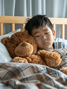棕熊摄影照片_亚洲男孩患流感棕熊躺在病床上治