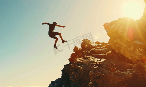 跳跃剪影摄影照片_一名运动员在岩石悬崖上跳跃的剪影