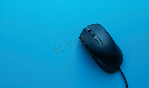蓝色背景中黑色游戏光学鼠标的特写
