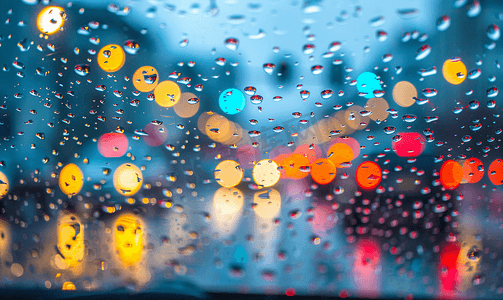 汽车玻璃上的雨滴和彩色交通散景灯