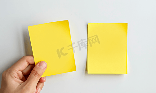 黄色闪粉摄影照片_两张空白的黄色便签用手指放在白板上