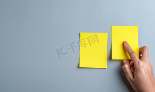 黄色页面摄影照片_两张空白的黄色便签用手指放在白板上