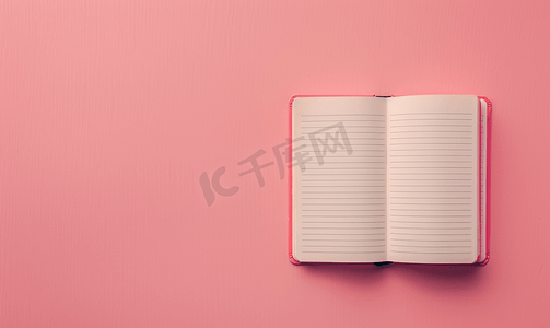 教育摄影照片_柔和的粉色彩色背景上打开空笔记本的顶部视图