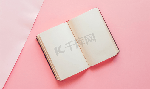 柔和的粉色彩色背景上打开空笔记本的顶部视图