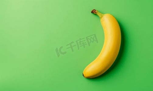 鲜绿色背景上成熟的单根香蕉最小的平铺顶视图复制空间