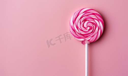 圆圈棒棒糖摄影照片_粉红色背景上甜美可口的粉红色棒棒糖最小的平面布局带有复制空间
