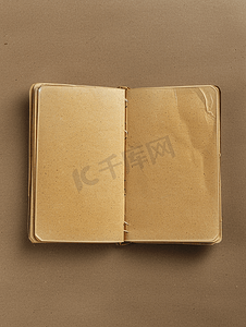 商业封面摄影照片_打开的空笔记本的顶视图封面由棕色背景的再生纸制成