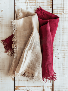 质朴的白色木质背景中米色和勃艮第颜色的布餐巾的顶部视图