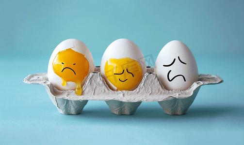 破裂的鸡蛋壳摄影照片_纸蛋托盘中有趣的鸡蛋和悲伤的破裂鸡蛋