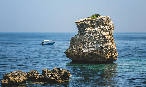 一艘小船经过黎巴嫩贝鲁特海岸的一块大岩石