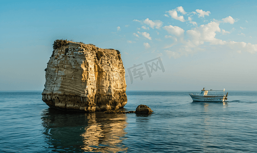黎巴嫩国徽摄影照片_一艘小船经过黎巴嫩贝鲁特海岸的一块大岩石