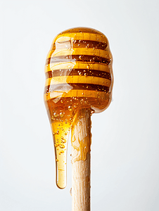 美味的蜂蜜摄影照片_白色背景下用木棒制成的蜂蜜