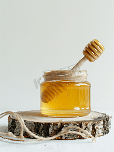 美味的蜂蜜摄影照片_白色背景下用木棒制成的蜂蜜